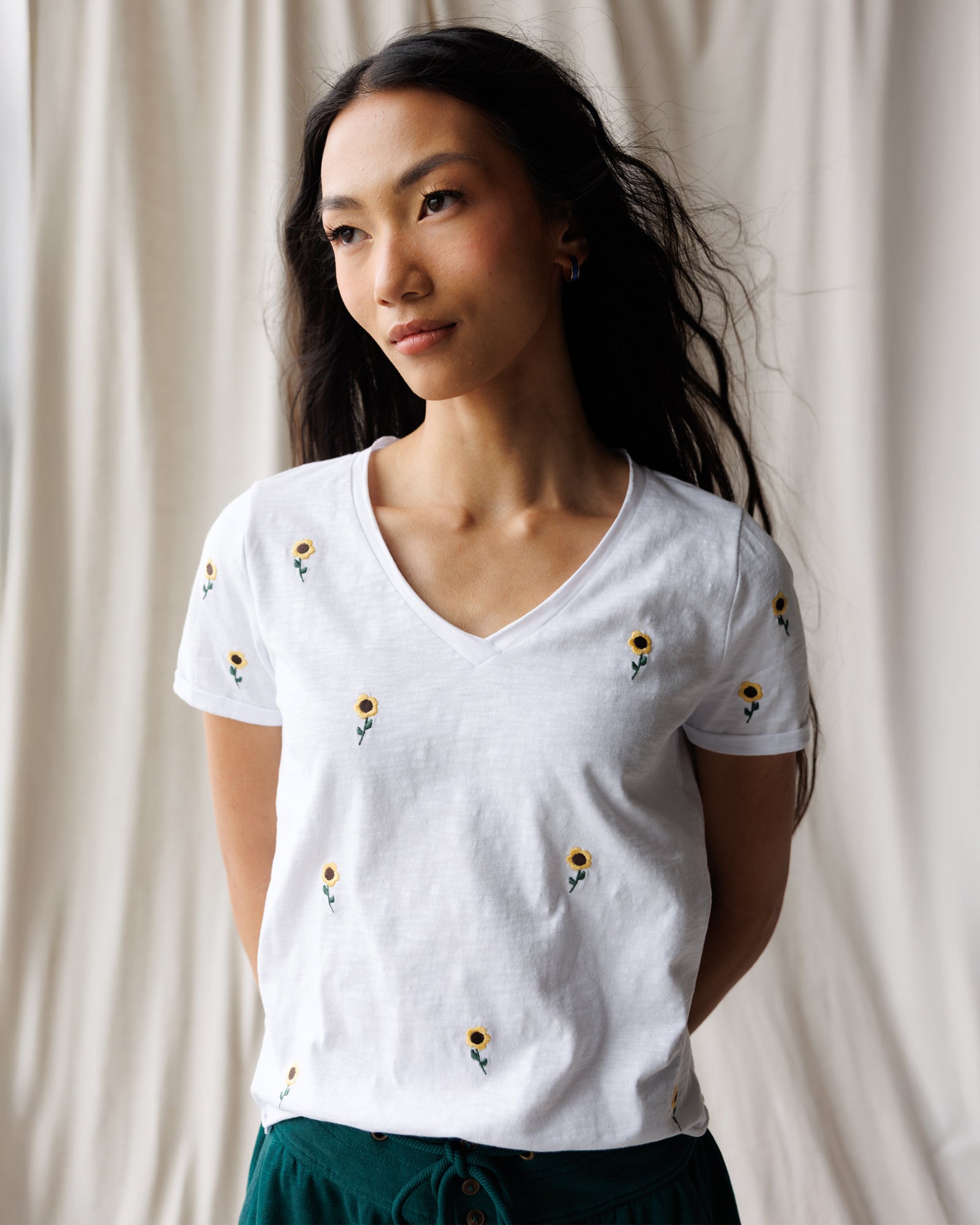 Woman wearing a white t-shirt with floral patterns against a neutral background