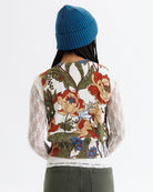 Person wearing a floral-patterned shirt with sheer sleeves on a white background