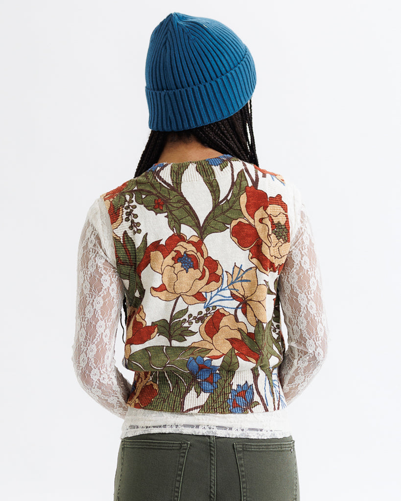 Person wearing a floral-patterned shirt with sheer sleeves on a white background