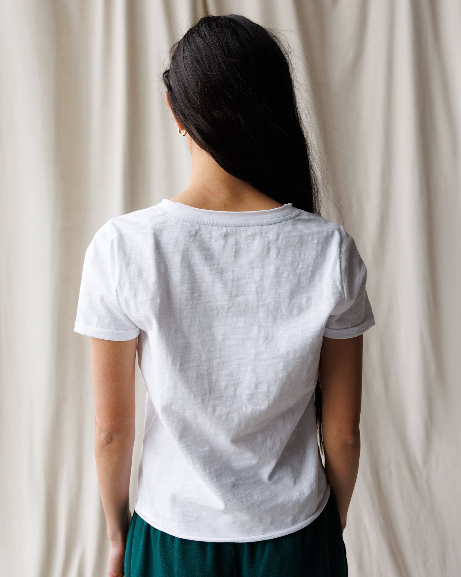 Person wearing a plain white t-shirt against a neutral background