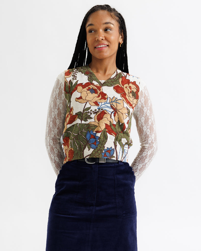 Woman wearing a floral top with sheer sleeves against a white background