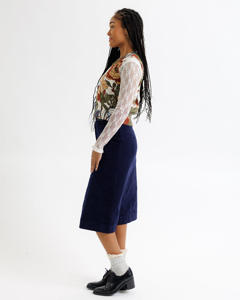 Person wearing a floral top and navy skirt on a white background