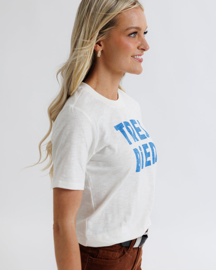 Woman wearing a white t-shirt with blue text on a plain background