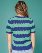 Person wearing a blue and green striped sweater against a teal background