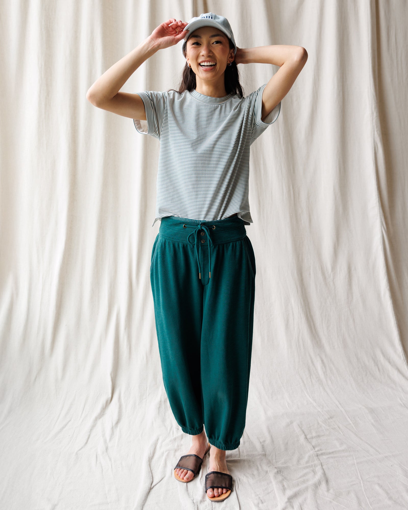Person wearing a gray t-shirt and teal pants against a white background