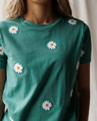 Green t-shirt with white daisy flowers on a neutral background