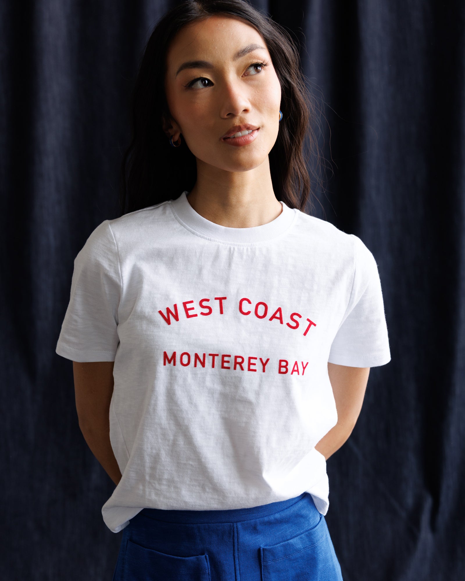 Person wearing a white t-shirt with 'West Coast Monterey Bay' text against a dark background