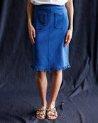 Person wearing a blue skirt against a dark background