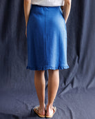 Person wearing a blue skirt against a dark background
