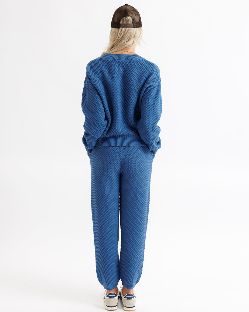 Person wearing a blue sweater and pants set on a white background