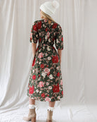 Back view highlighting the all-over smocked bodice for a flexible fit, subtle keyhole button back closure, and softly gathered skirt falling below the knee.
