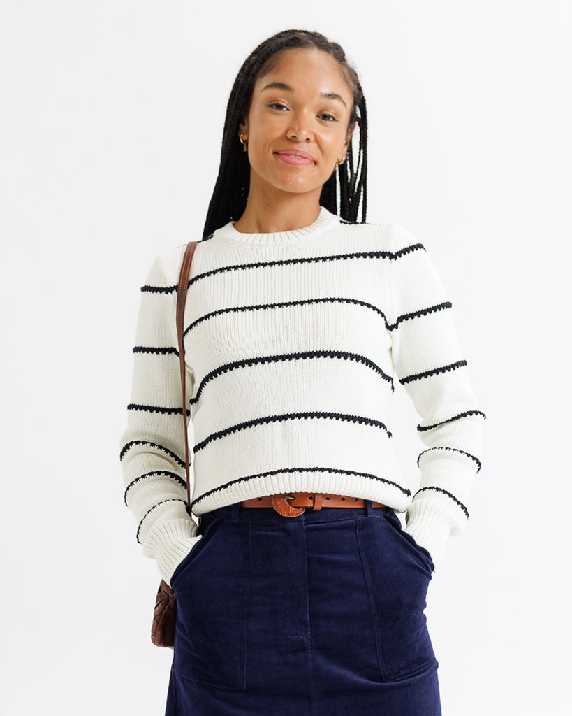 Woman wearing a white sweater with black stripes on a white background