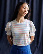 Woman wearing a striped shirt and blue skirt against a navy background