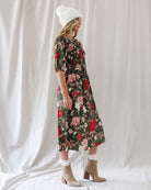 Side profile showing the fitted smocked torso, elasticized puff sleeve cuffs, and midi-length drape of the floral A-line dress.