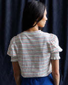 Woman wearing a striped shirt and blue skirt against a navy background