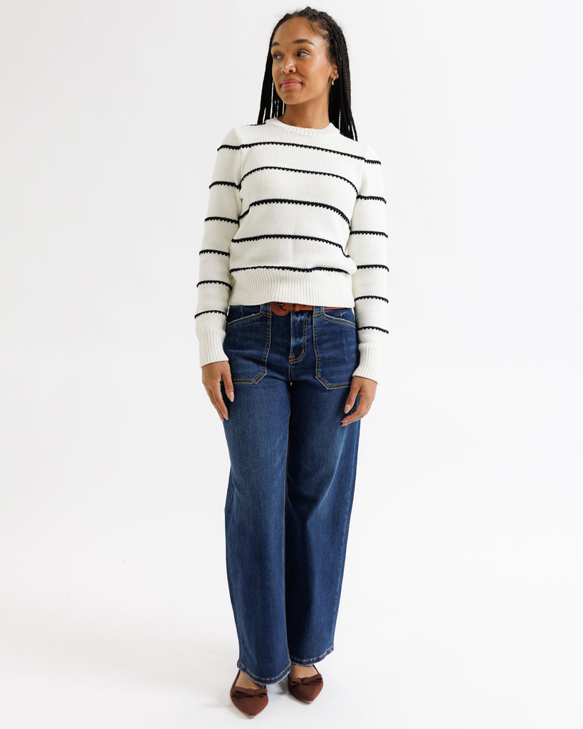 Person wearing a striped sweater and blue jeans on a white background