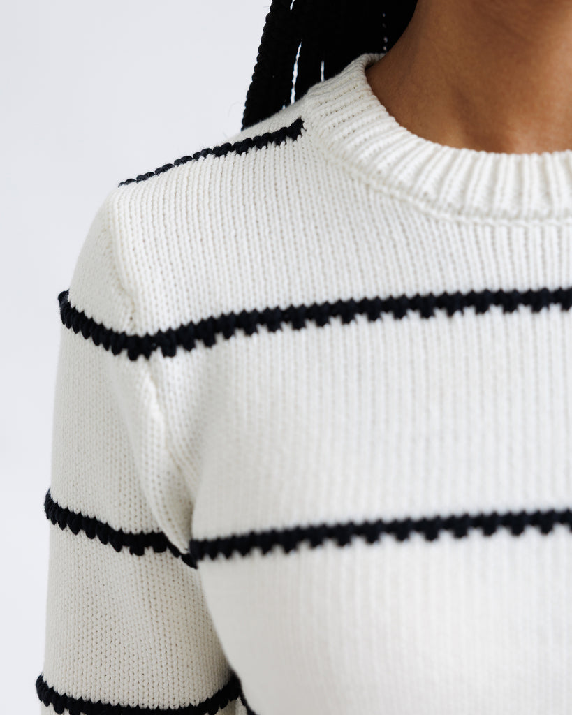 White sweater with black trim on a white background