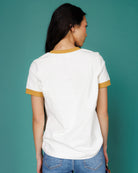 Person wearing a white t-shirt with yellow trim against a teal background