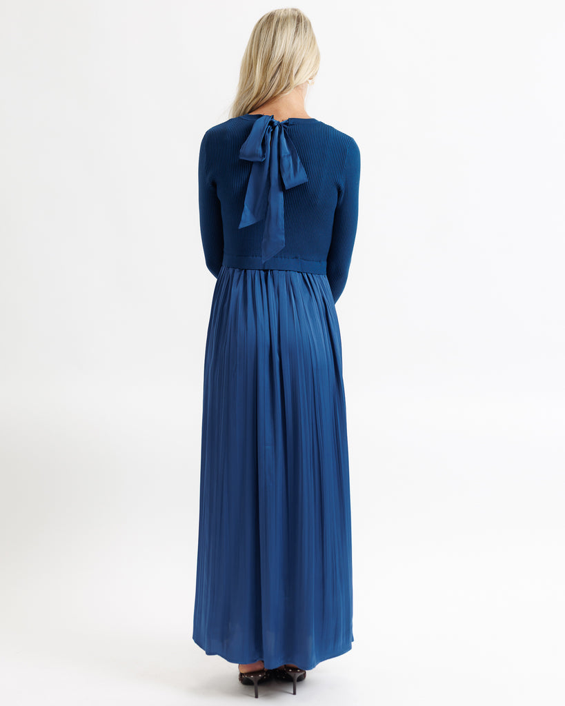 Woman wearing a blue dress with a bow detail on a white background