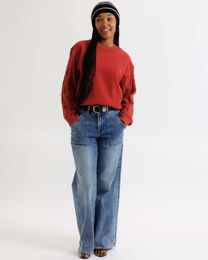 Person wearing a red sweater and blue jeans on a white background