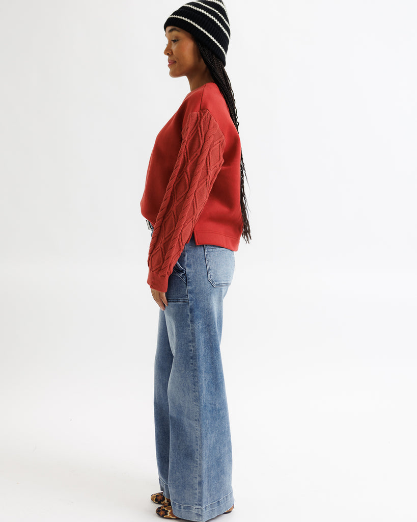 Person wearing a red sweater and blue jeans on a white background
