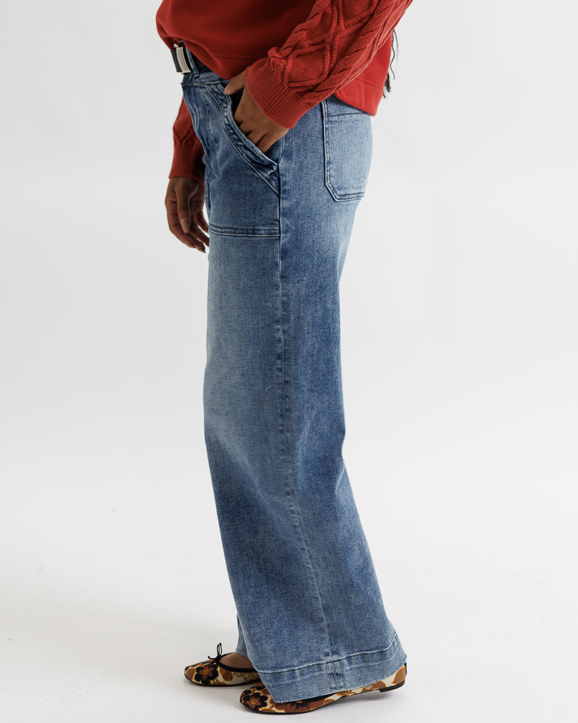Person wearing blue flared jeans and a red top on a white background