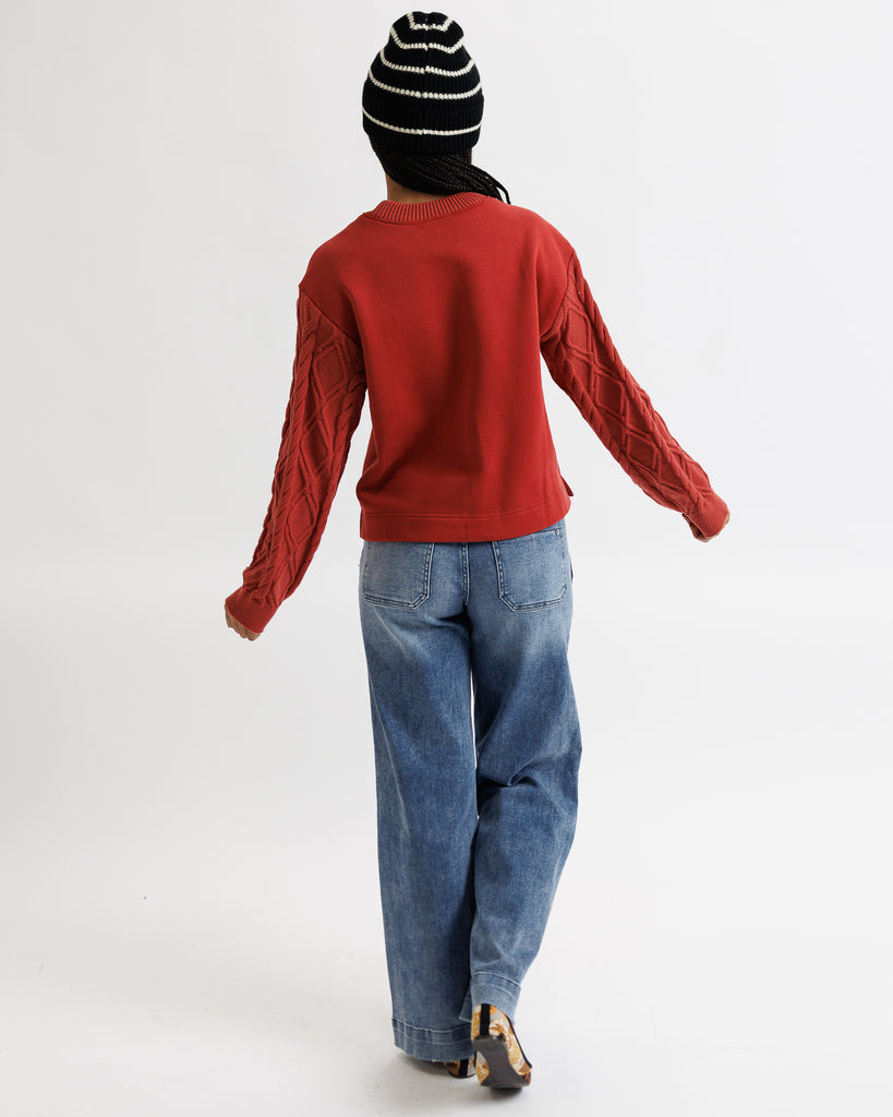 Person wearing a red sweater and blue jeans from behind on a white background