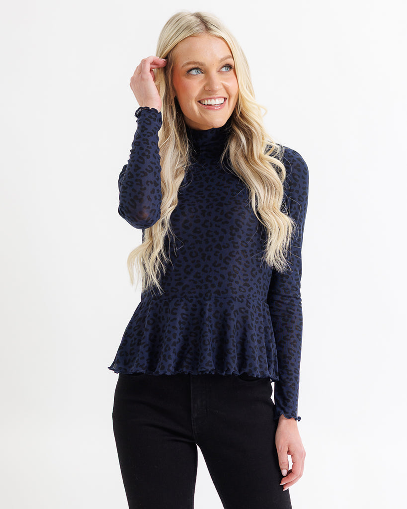 Woman wearing a navy blue patterned top on a white background