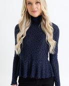 Woman wearing a navy blue leopard print long-sleeve top against a white background