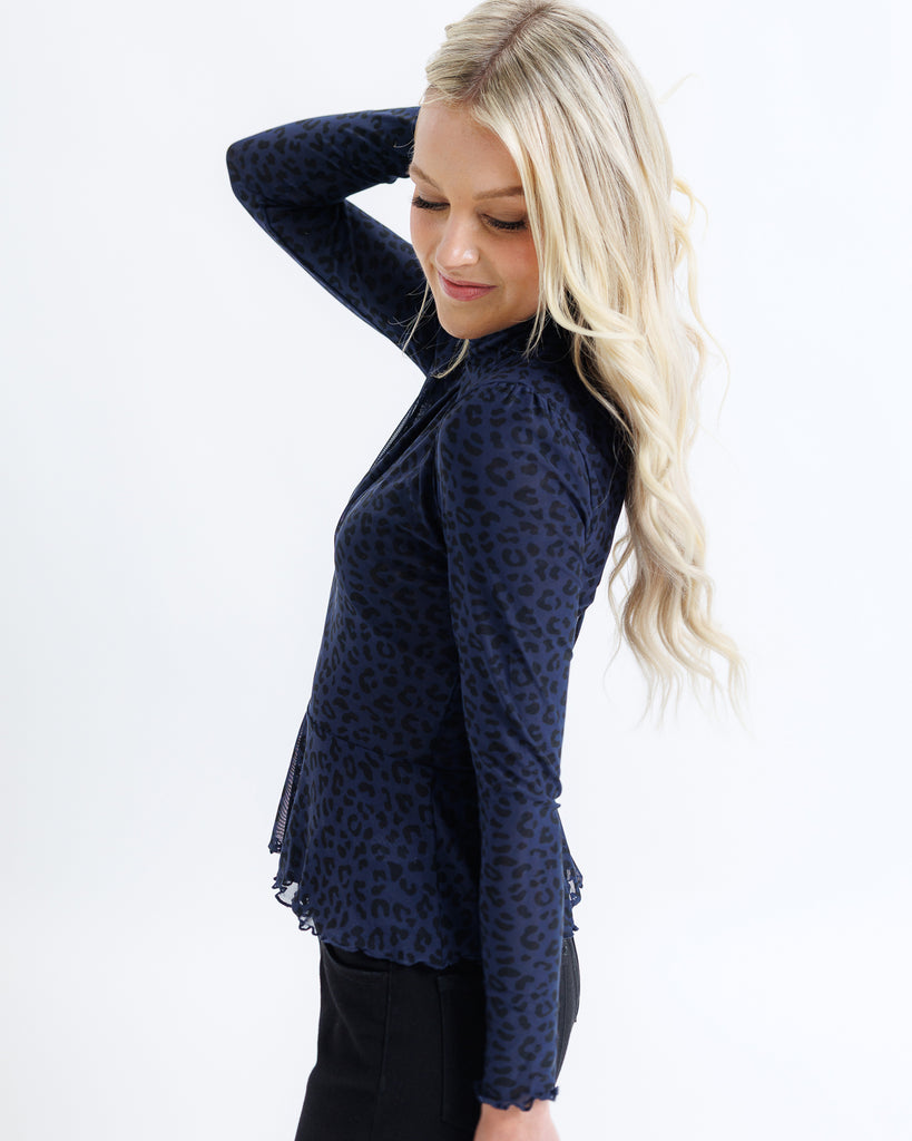 Woman wearing a navy blue patterned top on a white background