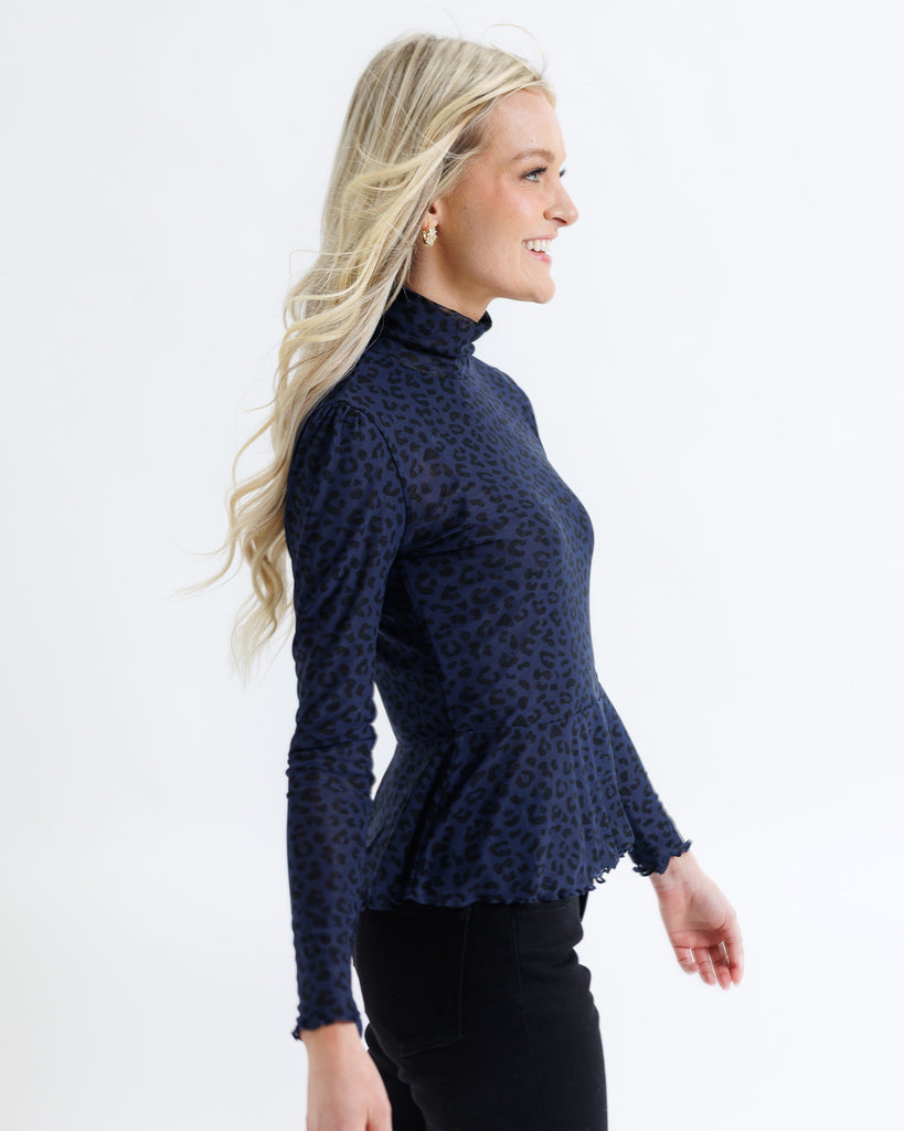 Woman wearing a navy blue patterned top on a white background