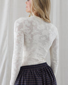 Back view highlighting the seamless fitted cut, fine ribbed crew neckband, and allover tonal floral jacquard lace pattern of the cream long-sleeve shirt