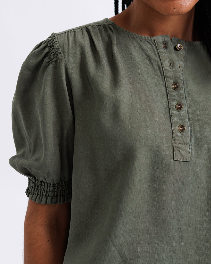 Green blouse with puff sleeves and button details on a white background