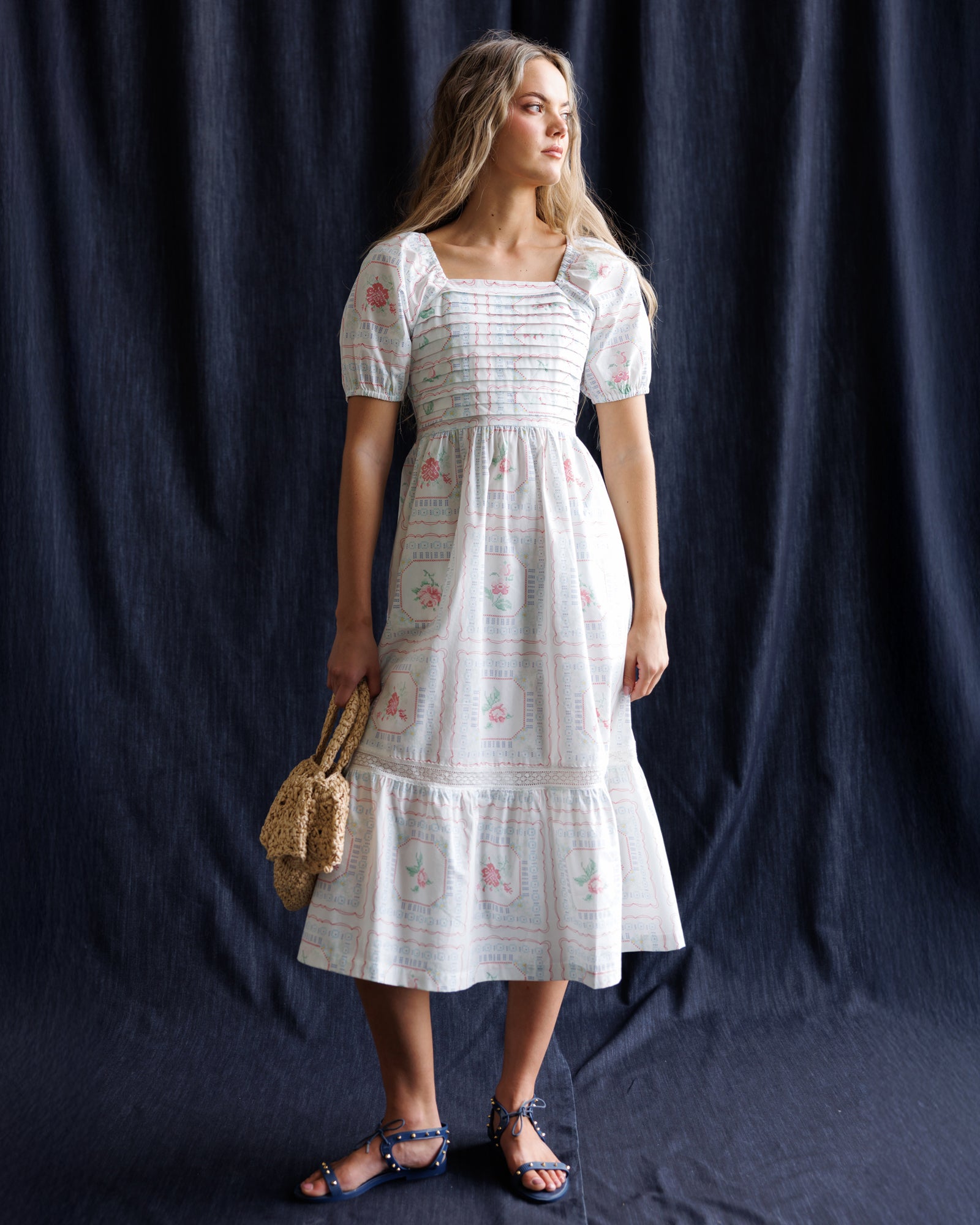 Woman wearing a white dress with floral patterns against a dark background