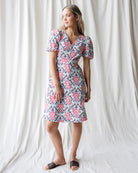 Woman wearing a floral dress standing against a white curtain