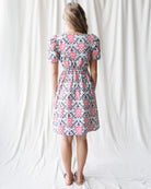 Woman wearing a floral dress standing against a white curtain