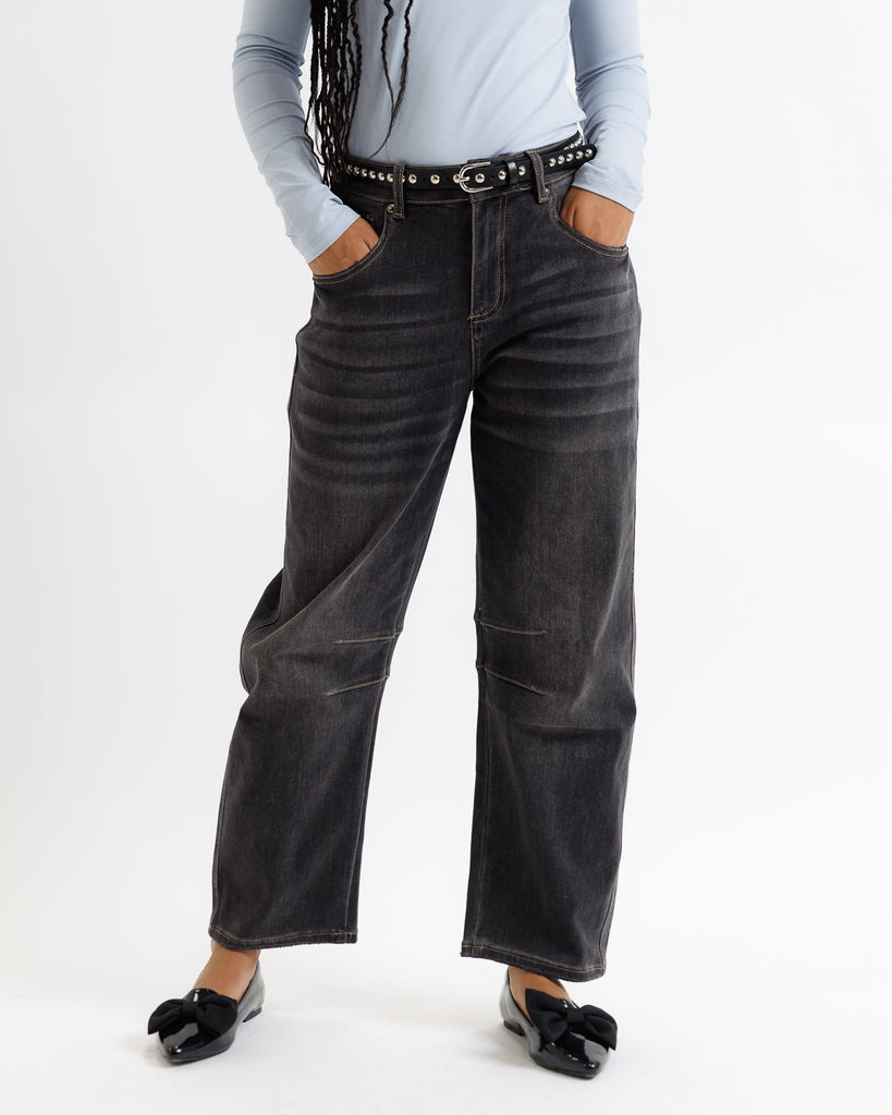 Person wearing black wide-leg jeans with a light blue shirt on a white background