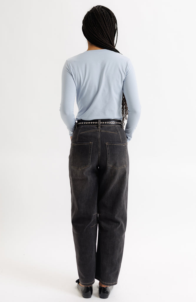 Person wearing a light blue shirt and dark jeans on a white background