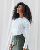 Angled front view highlighting the close, tailored fit of the white and navy striped long-sleeve shirt, featuring set-in angled shoulder seams and a banded crewneck.