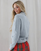 Side angled view showing the raglan shoulder seams, relaxed sleeve silhouette, and hip-length fit of the soft grey knit pullover.
