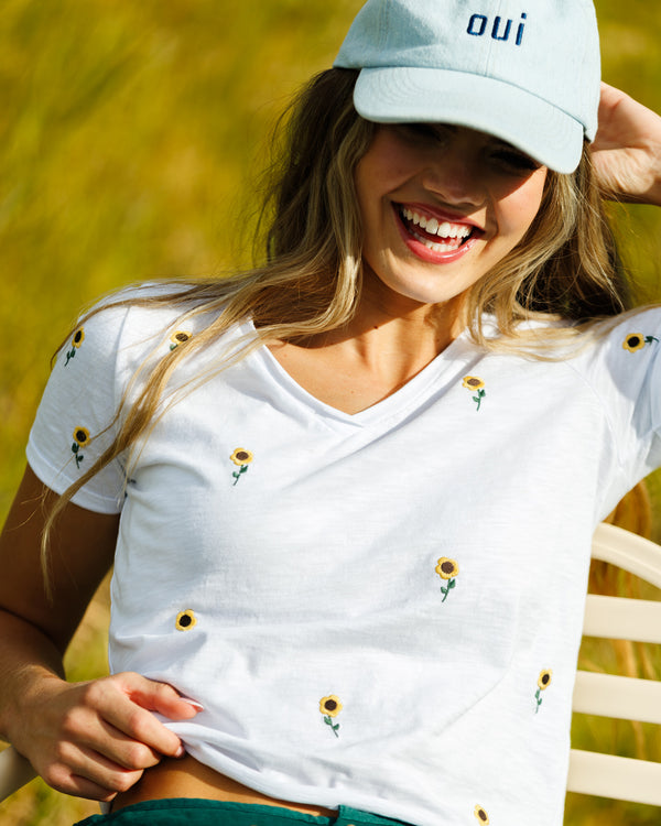 Woman wearing a white tee with sunflower embroidery 