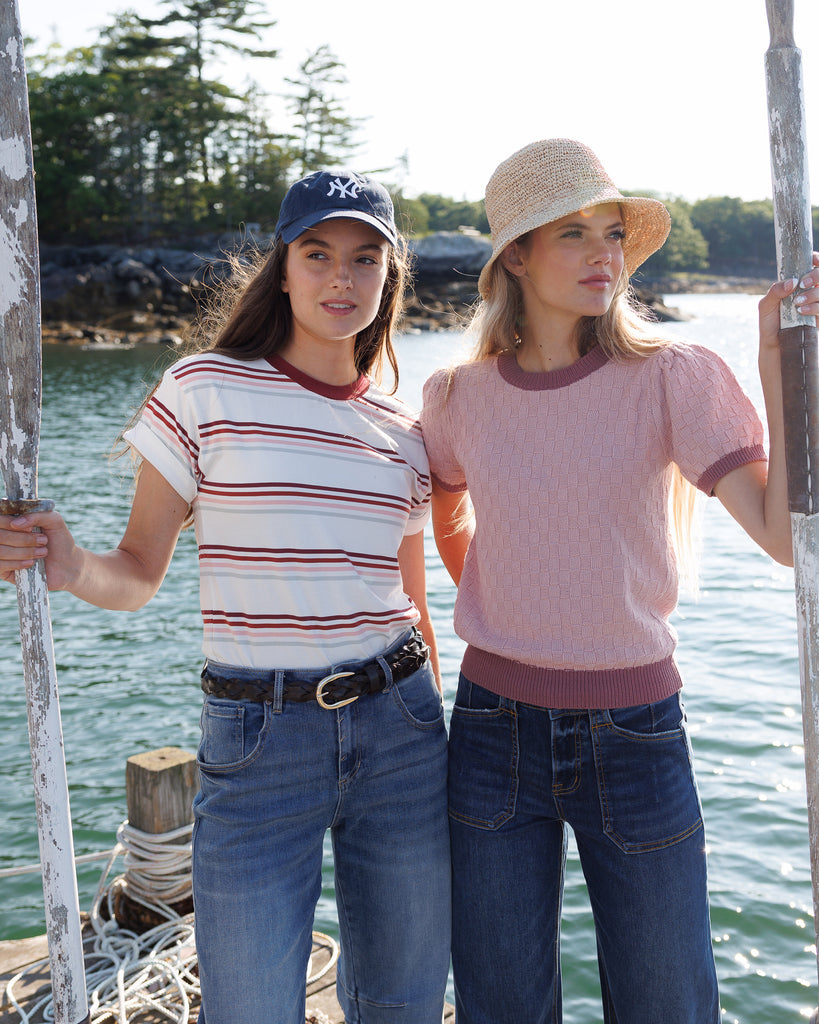 Two women standing by a body of water, wearing casual clothing.