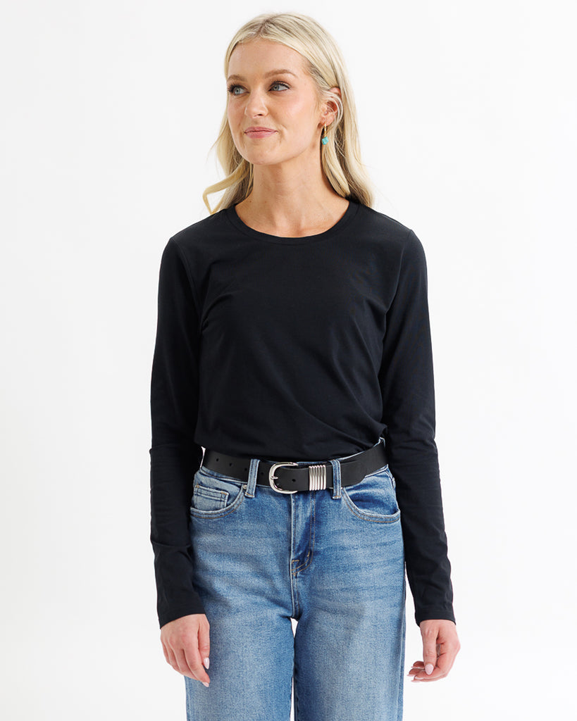 Woman wearing a black long-sleeve top and blue jeans on a white background