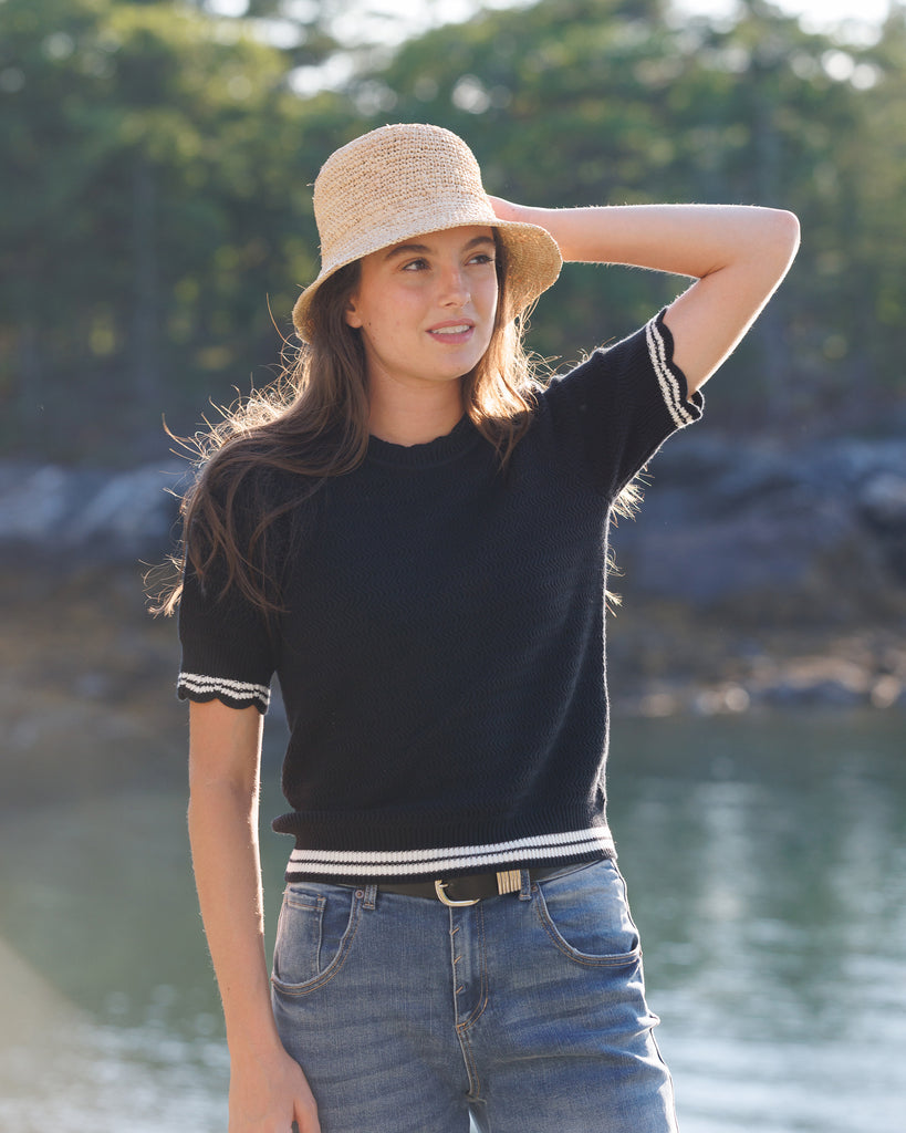 Model wearing a black short sleeve pullover sweater with white edging details on the sleeves and waist.