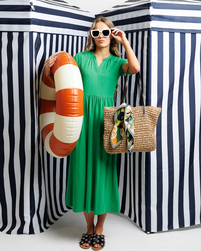 Model wearing a green short sleeve v-neck midi length knit dress