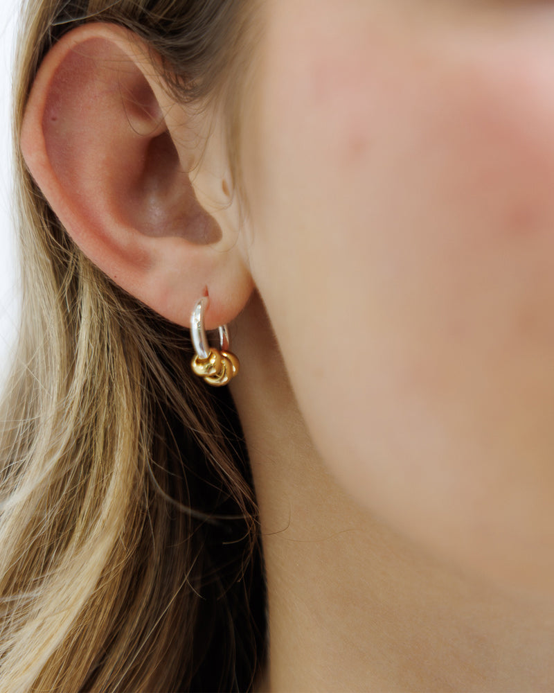 Close-up of an ear wearing a gold and silver hoop earring.