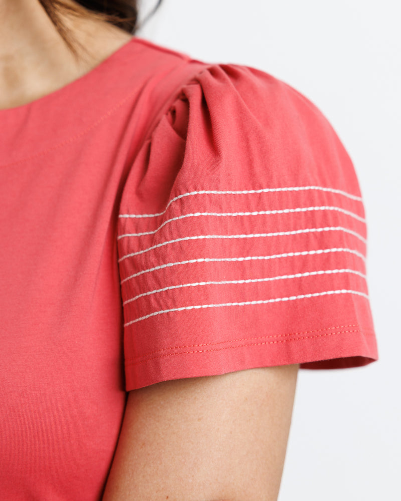 Model wearing a red round neck short sleeve t-shirt with stitching on arms