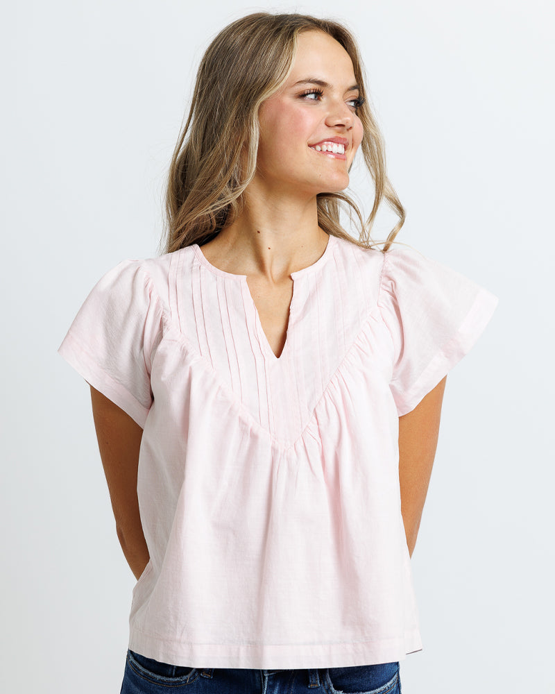 Model wearing a pink short flutter sleeve, v-neck blouse