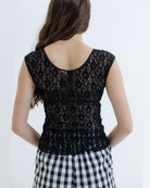 Person wearing a black lace top and checkered pants on a white background