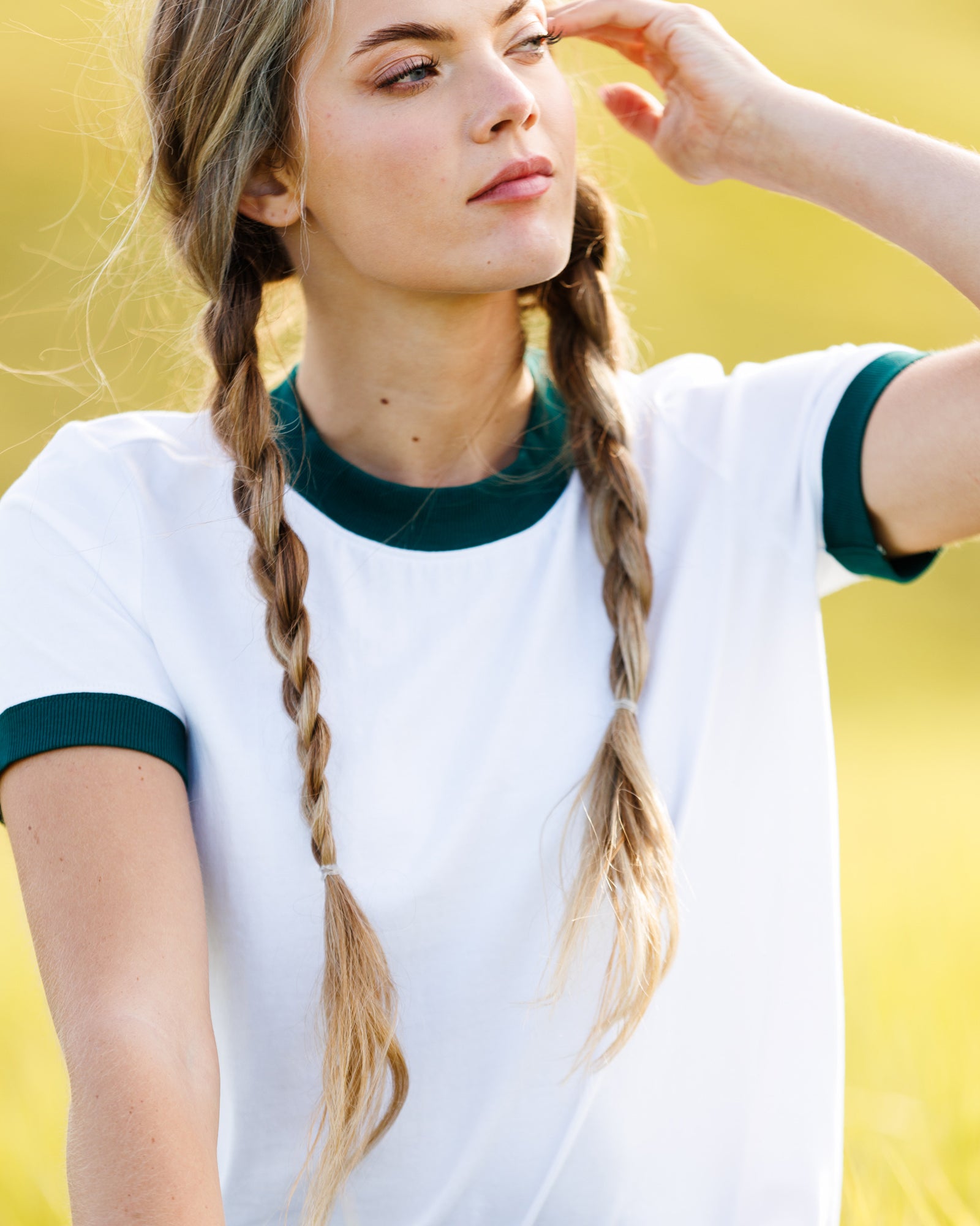 Person wearing a white ringer shirt with green trim against a yellow background